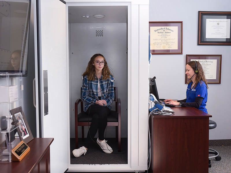 Lady in hearing booth having hearing tested